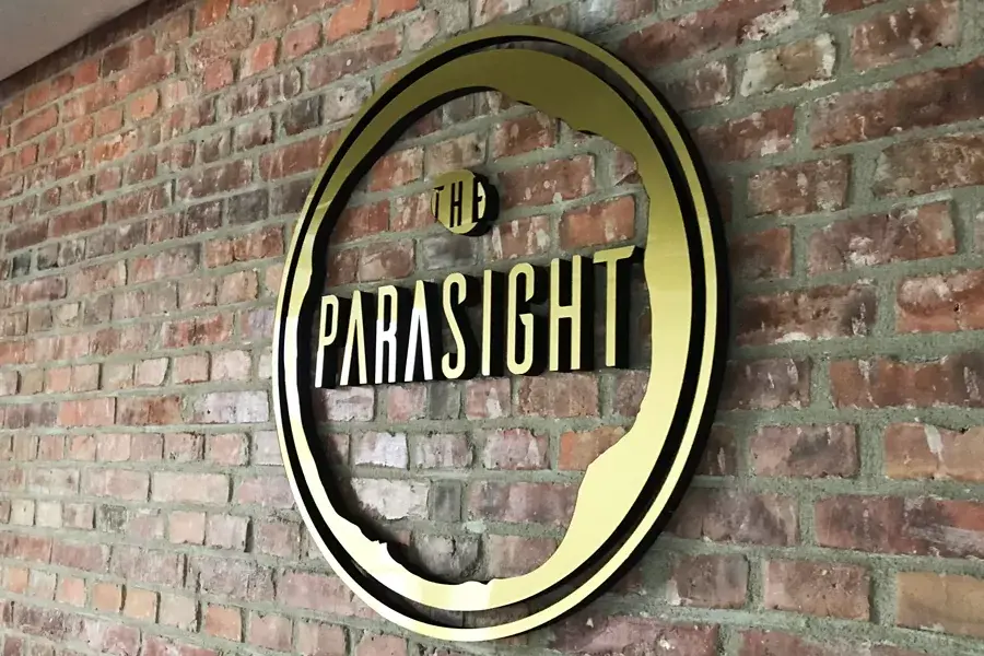 Kruhové 3D logo The Parasight na cihlové stěně — realizace Neonworld